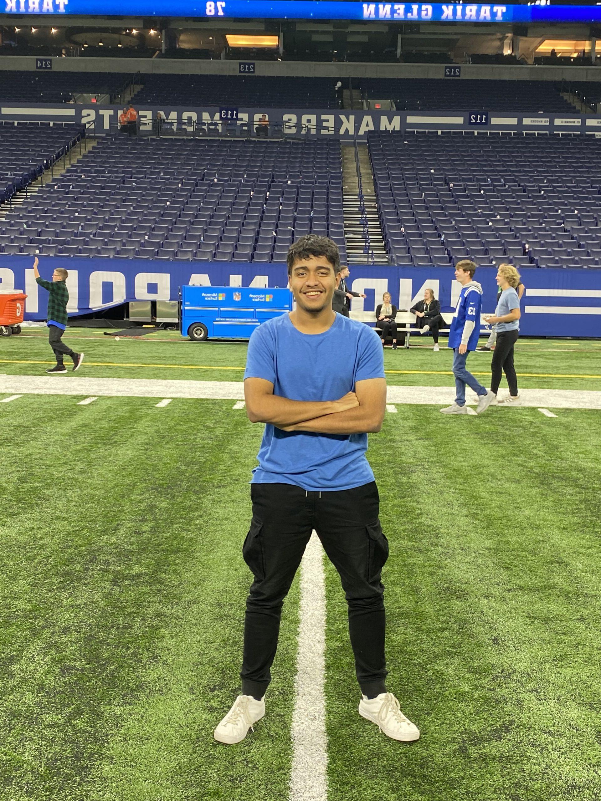 Male student stands on a football field